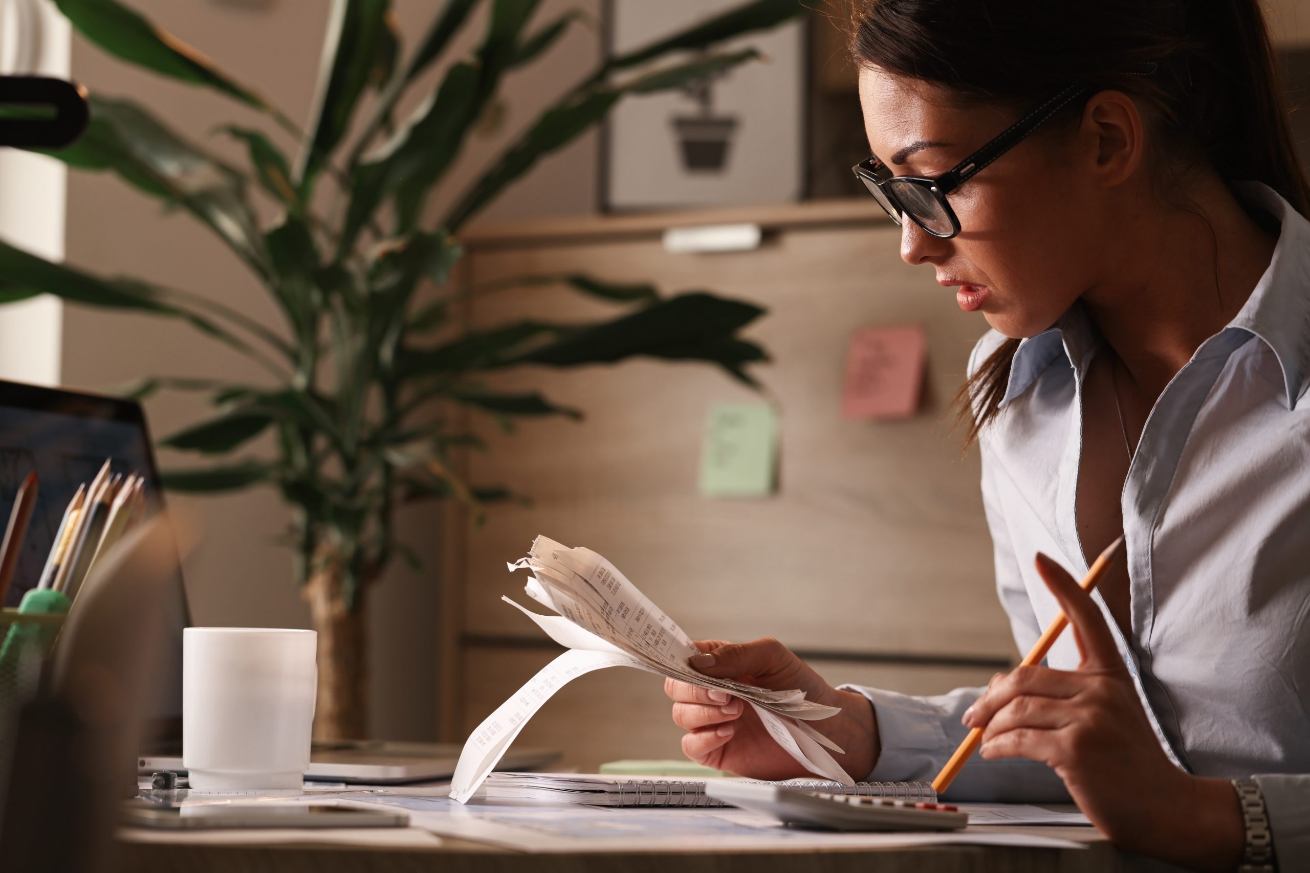 Young businesswoman going through finances and analyzing bills in the office.